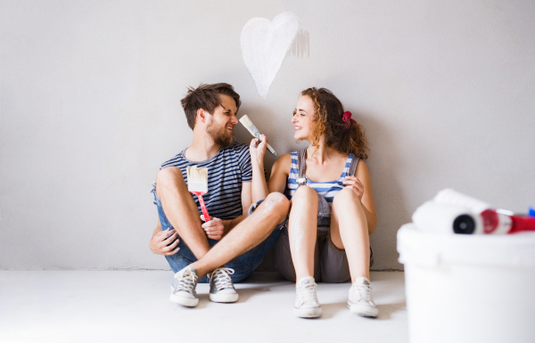 Beautiful young couple in love having fun, painting walls of their new house. Home makeover and renovation concept.