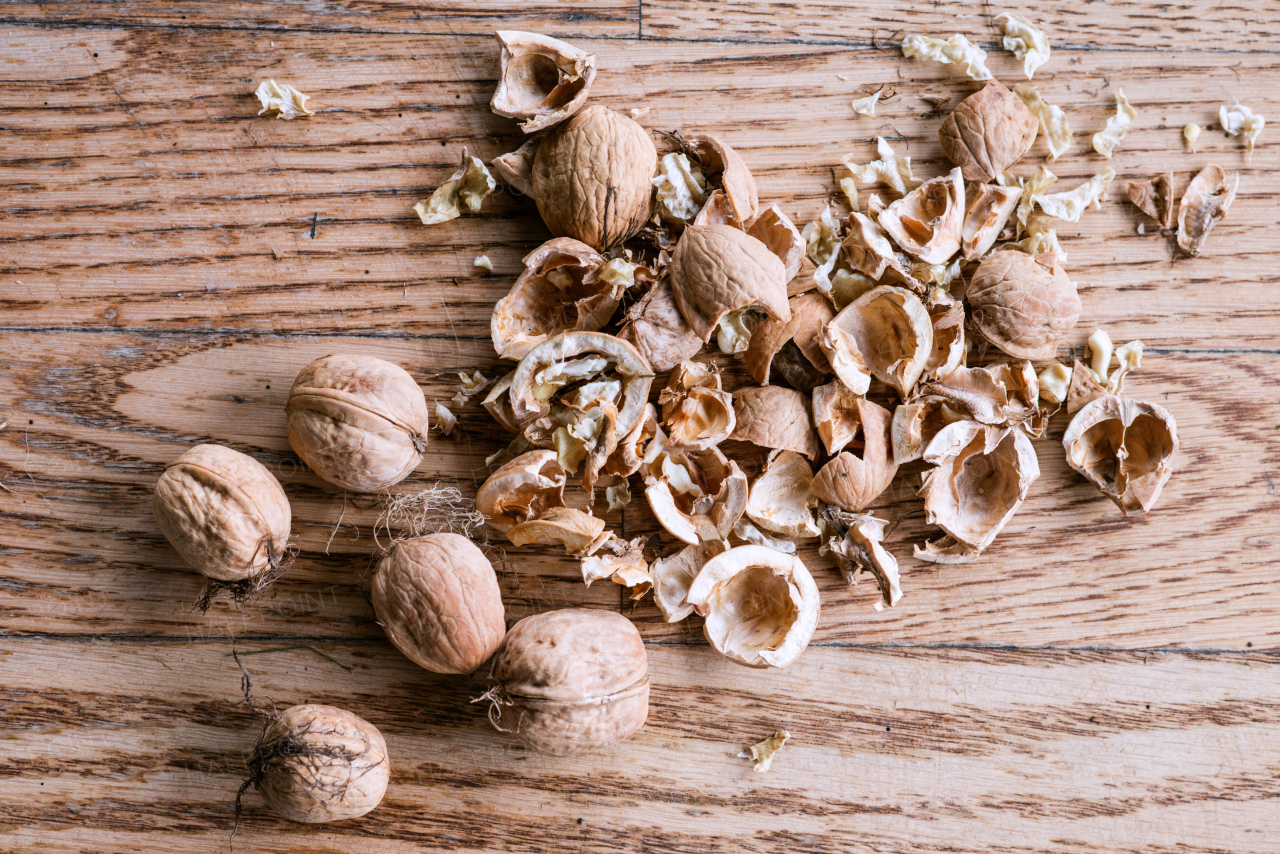 Heap of cracked and whole walnut fruits on wooden background. Studio shot.