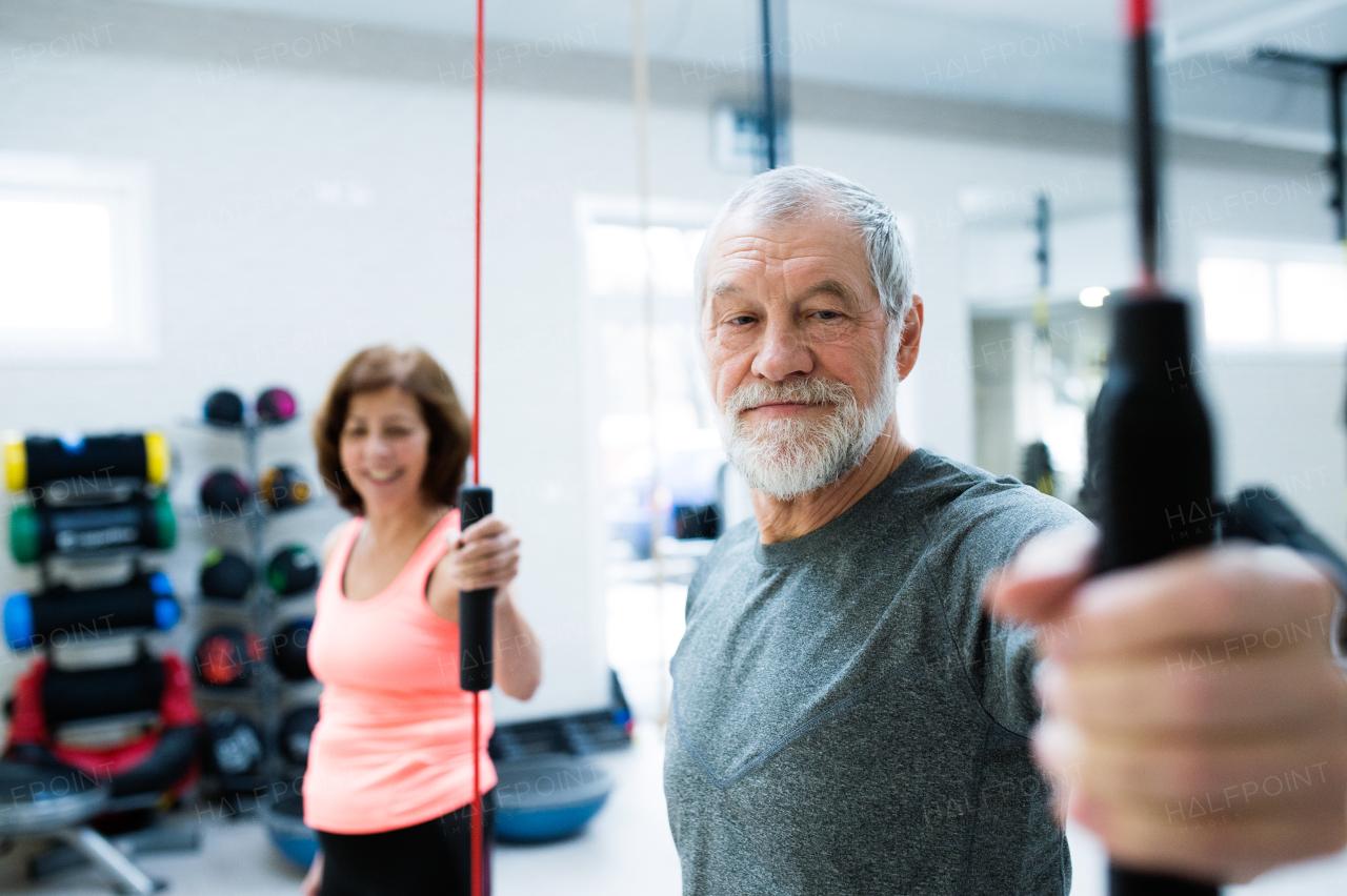 Beautiful fit senior couple in gym working out with vibration bars