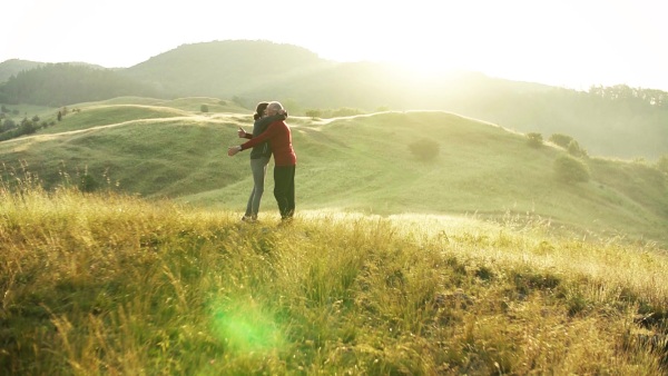 Senior couple runners hugging on meadow outdoors at sunrise in nature. Slow motion.