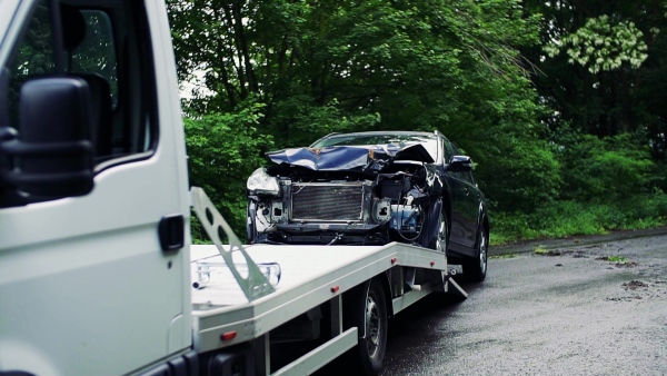 A crashed car being put on a tow truck after an accident. Towing service concept. Slow motion.