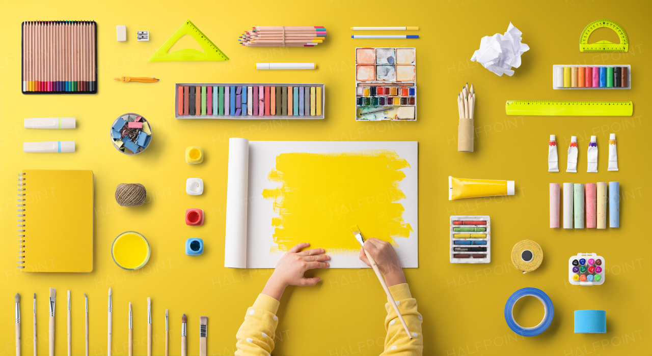 A flat lay top view of child hands with school supplies, back to school concept.