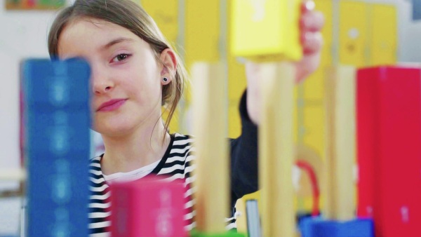 A small girl learning at the desk at school. Slow motion. Close up.