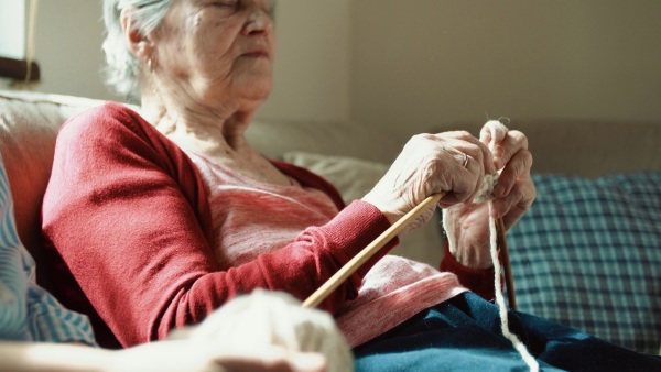 Unrecogniazable elderly grandmother and adult granddaughter at home, knitting. Close up.