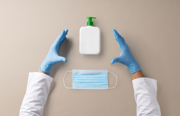 Hands of healthcare worker with gloves, face mask and antiseptic gel, covid-19 concept.