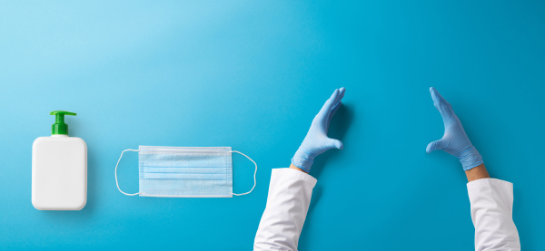 Hands of healthcare worker with gloves, face mask and antiseptic gel, covid-19 concept. Copy space.