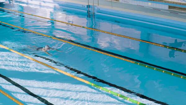 Senior man swimming in an indoor swimming pool. Active pensioner enjoying sport.