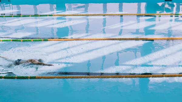 Senior man swimming in an indoor swimming pool. Active pensioner enjoying sport.