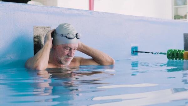 Senior man in an indoor swimming pool. Active pensioner enjoying sport.