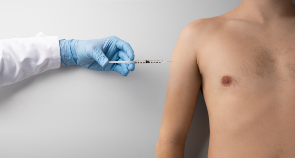 Hand with syringe injection and topless mans torso, covid-19 and vaccination concept. Copy space.