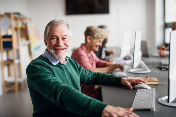 Portrait of senior man attending computer and technology education class, looking at camera.