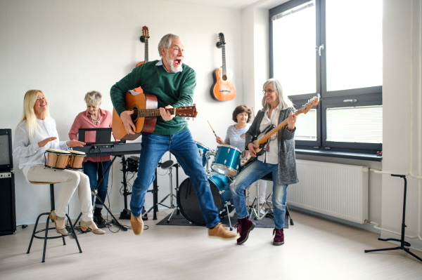 Group of senior people playing musical instruments indoors in band, having fun.