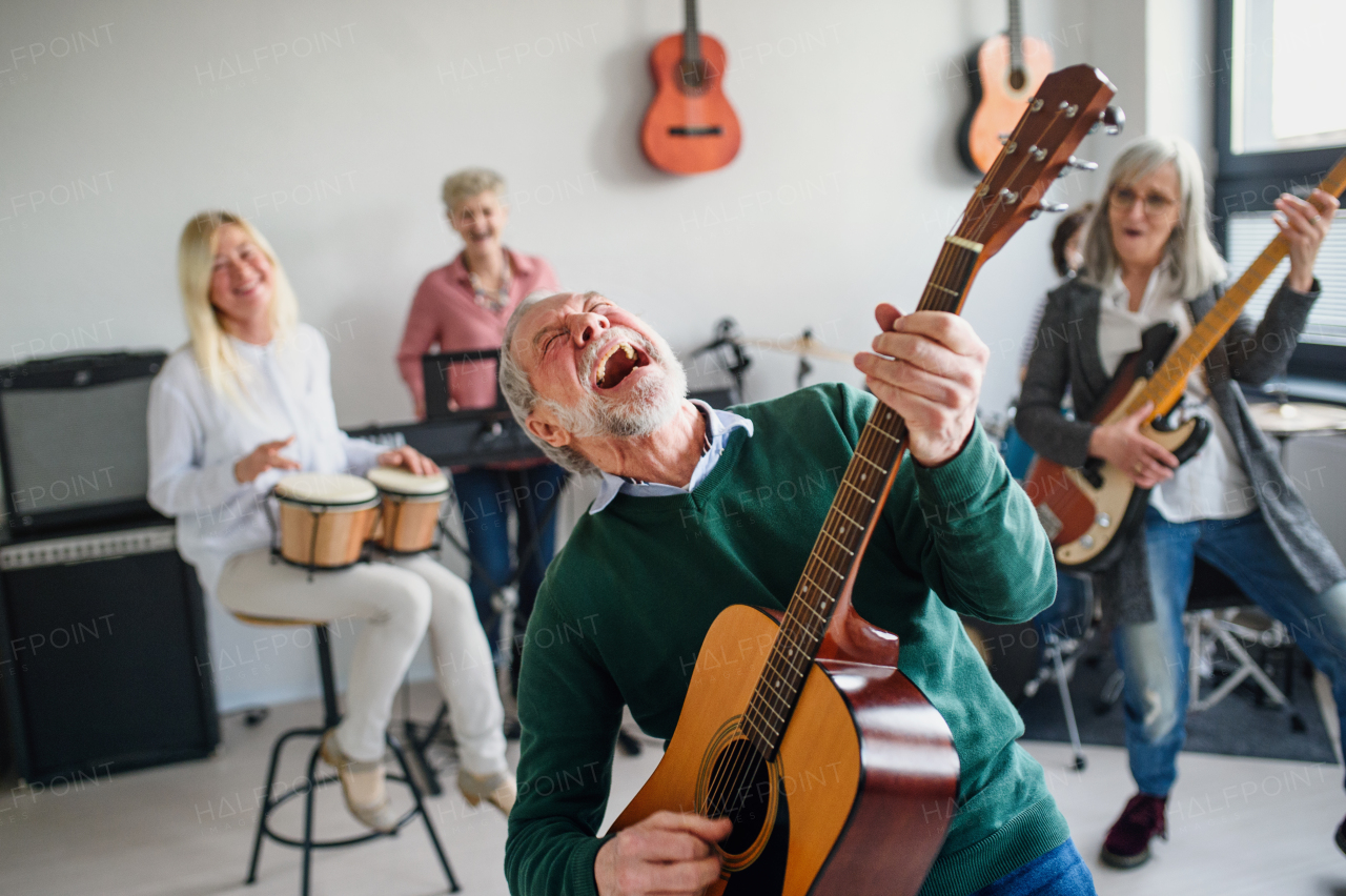 Group of senior people playing musical instruments indoors in band, having fun.