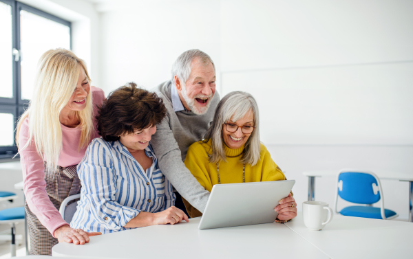 Group of cheerful senior people attending computer and technology education class.