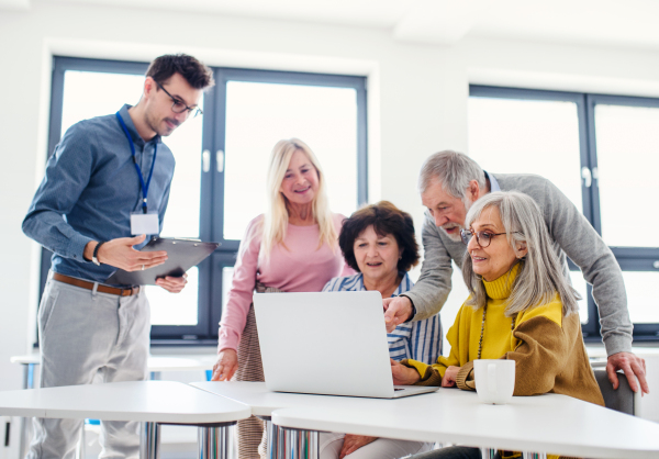 Group of cheerful senior people attending computer and technology education class.