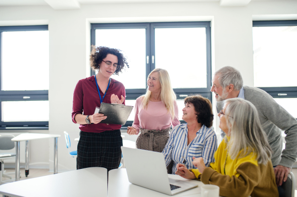 Group of cheerful senior people attending computer and technology education class.