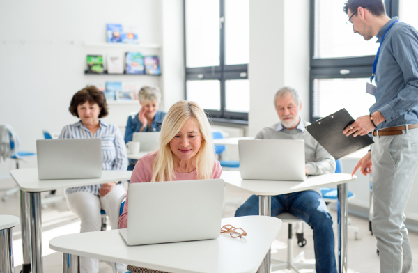 Group of cheerful senior people attending computer and technology education class.