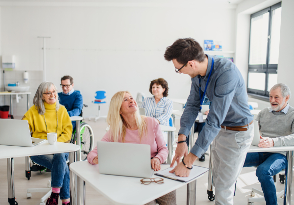 Group of cheerful senior people attending computer and technology education class.