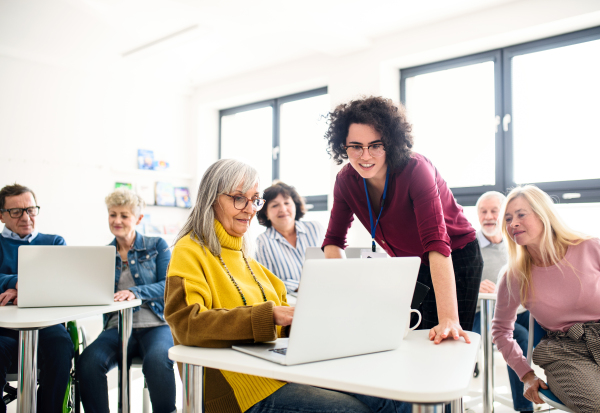 Group of cheerful senior people attending computer and technology education class.