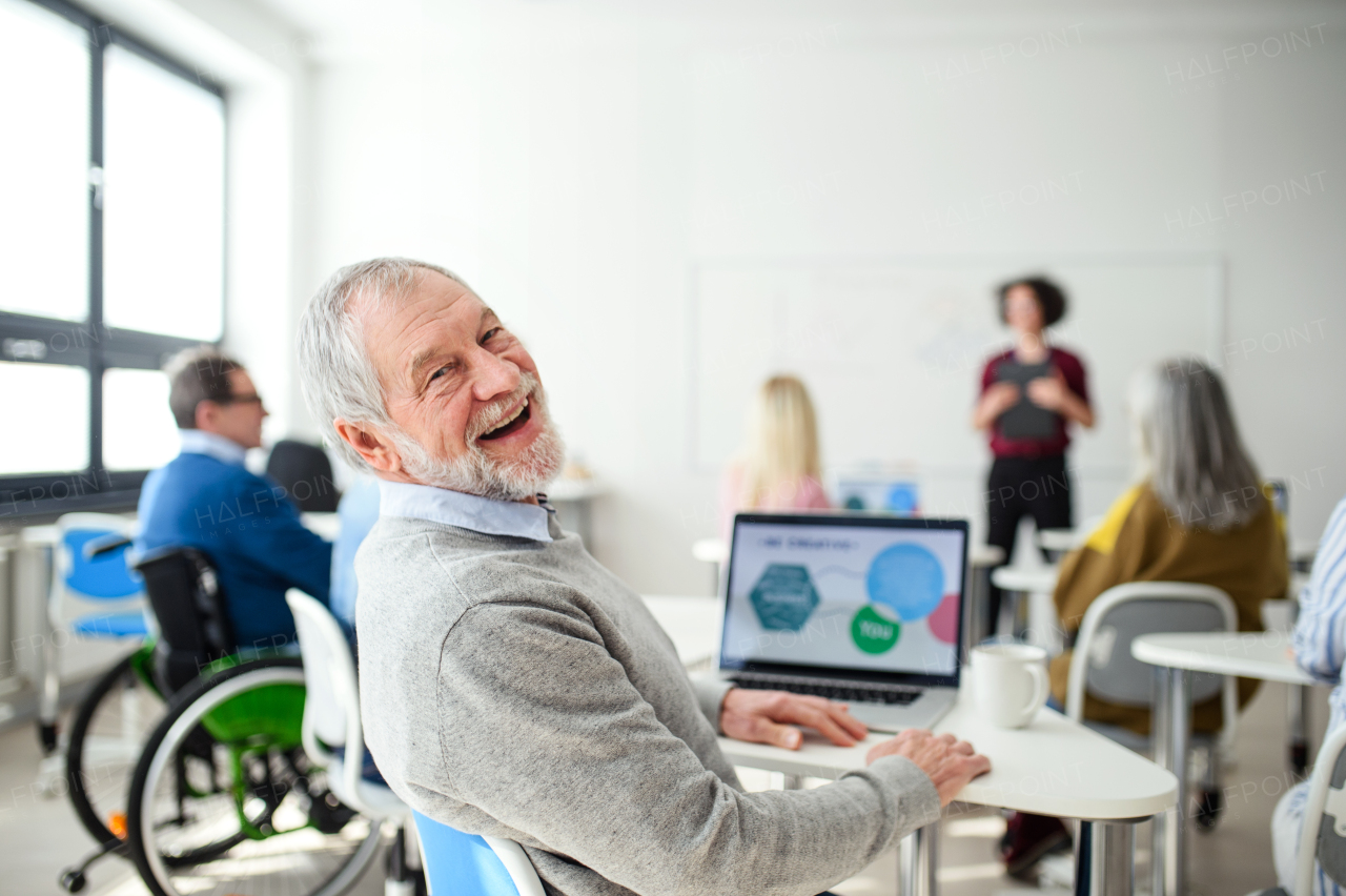 Portrait of senior man attending computer and technology education class, looking at camera.