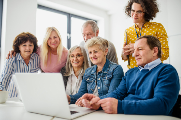 Group of cheerful senior people attending computer and technology education class.