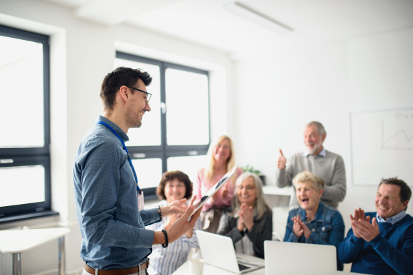 Group of cheerful senior people attending computer and technology education class, clapping.