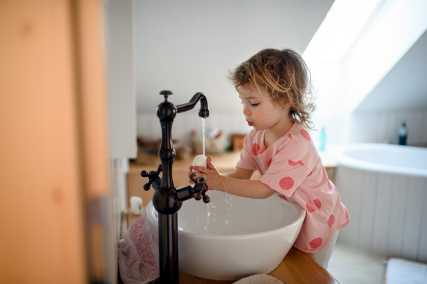 Side view of concentrated small toddler girl washing hands, corona virus and quarantine concept.