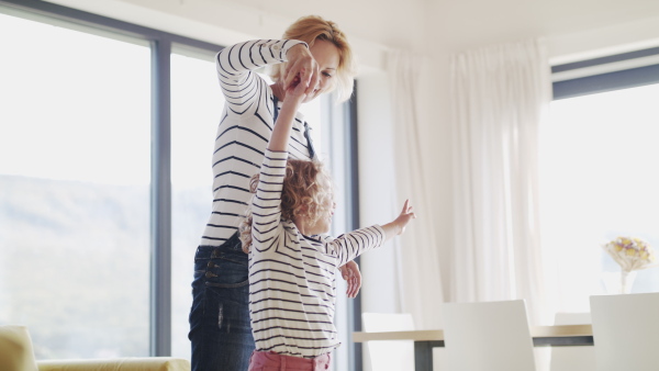 A cute small girl with mother indoors at home, playing.