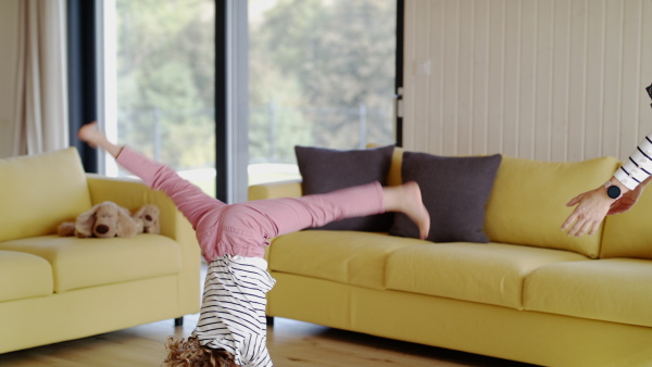 A cute small girl with unrecognizable mother indoors at home, playing.