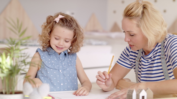 A cute small girl with mother in bedroom indoors at home, drawing pictures.