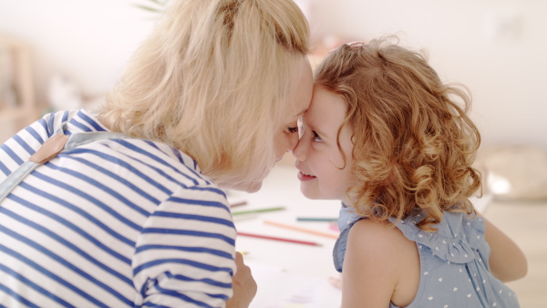 A cute small girl with mother in bedroom indoors at home, drawing pictures.