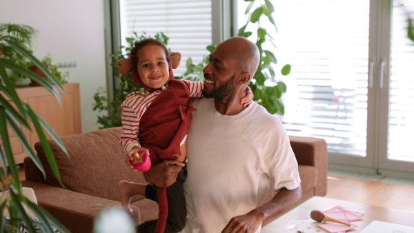 A multiracial father holding his little son in costume at home