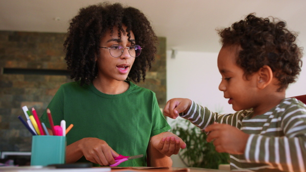 A big sister helping her little brother doing distance learning or schoolwork at home