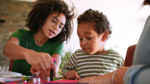 A big sister helping her little brother doing distance learning or schoolwork at home