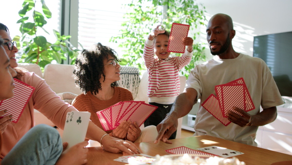 A happy multiethnic family enjoying time together at home, playing cards.