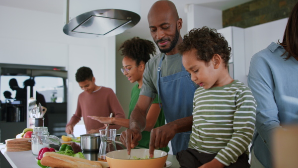 A happy multiracial family with three children cooking together at home.