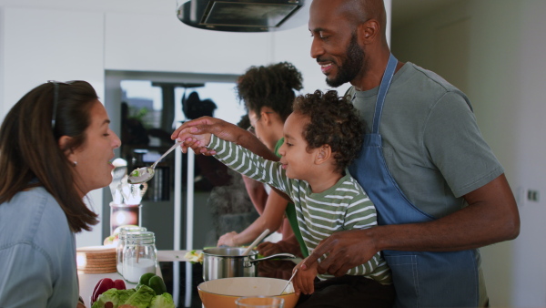 A happy multiracial family with three children cooking together at home.