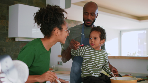 A happy multiracial family with three children cooking together at home.