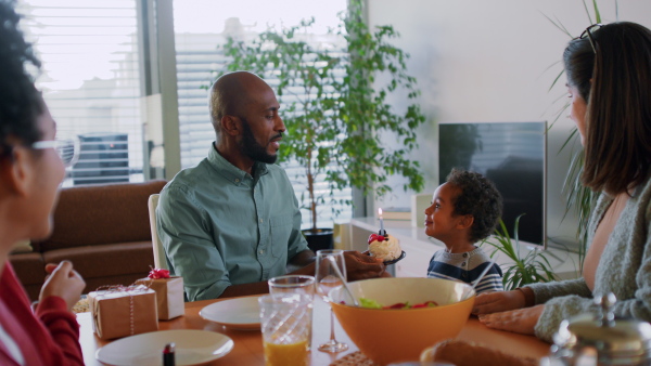 A little multiracial boy celebrating birthday with his family at home.