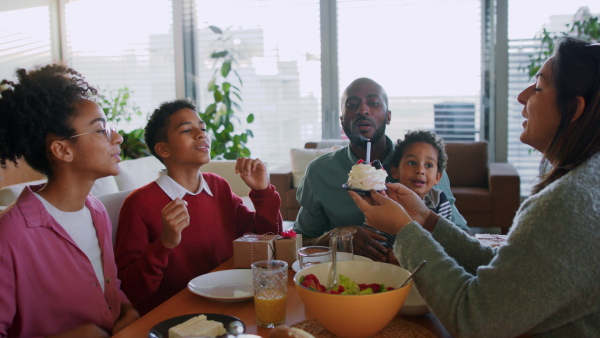 A little multiracial boy celebrating birthday with his family at home.