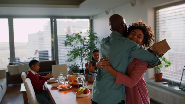 A mature African American father getting present from his teenage daughter at home.