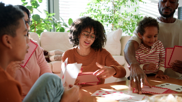 A happy multiethnic family enjoying time together at home, playing cards.