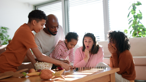 A happy multiethnic family enjoying time together at home, playing domino