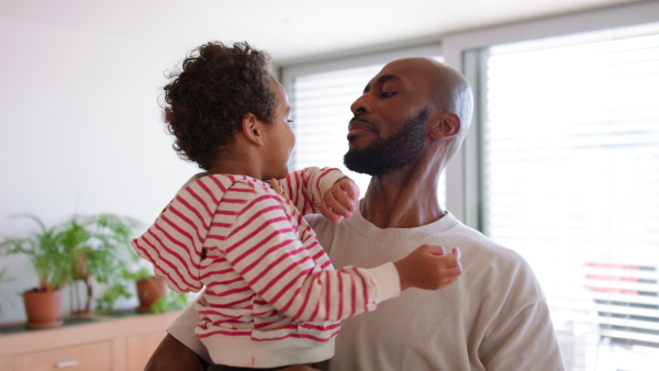 A multiracial father holding his little son at home