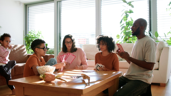 A happy multiethnic family enjoying time together at home, playing cards.