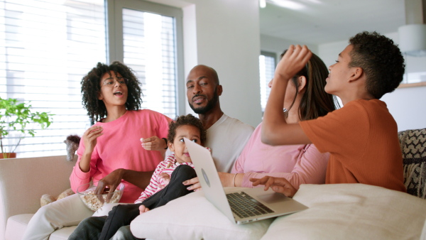 A happy multiethnic family enjoying time together at home, sitting on sofa.