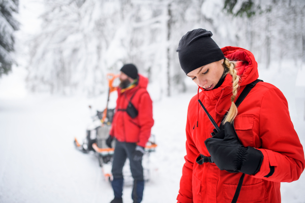 Paramedics from mountain rescue service provide operation outdoors in winter in forest, walking.