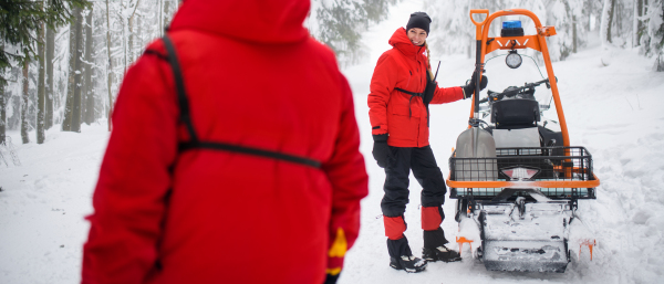 Paramedic woman from mountain rescue service provide an operation outdoors in winter in forest.