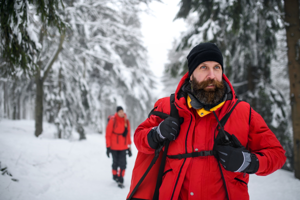 Paramedic man from mountain rescue service with walkie talkie outdoors in a winter in forest.