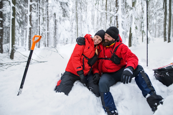 Mountain rescue service on operation outdoors in winter in forest, digging snow with shovels. Avalanche concept.